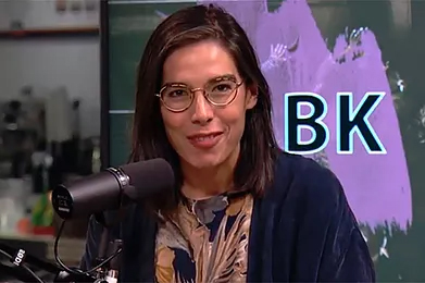 home-b-2 A woman with glasses is talking into a microphone.