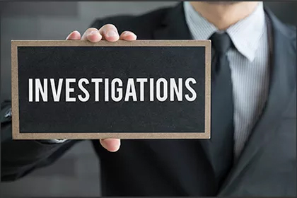A man holding up a sign that says investigations.