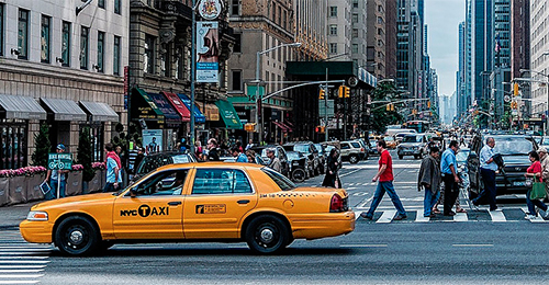 A taxi cab is driving down the street.